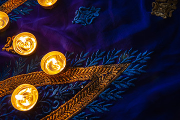 Flame candle lamps for the evening prayers. Diwali lighting on blue sari with golden embroidery