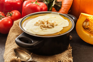 Pumpkin soup with cream and croutons in a pot