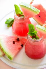 Summer watermelon smoothie decorated mint leaves on pink background. Summer drink concept
