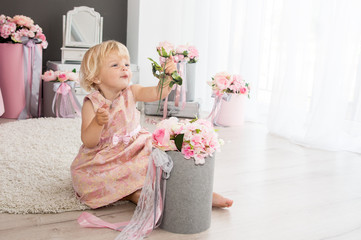 happy blond girl of two years playing in the decorated room for the holiday with a bouquet of flowers