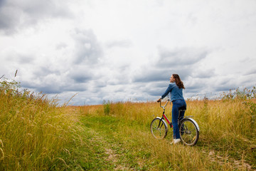 Happy Young Woman riding bicycle on a yellow field. Healthy Lifestyle.
