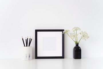 Black portrait square poster mock up with a Aegopodium podagraria in black vase and white vase with black pencils. . Template for small businesses, lifestyle bloggers, social media
