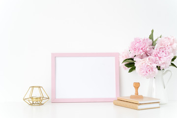 Pink landscape frame mock up with a pink peonies, candle and stamp beside the frame, overlay your...