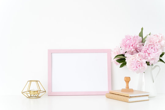 Pink landscape frame mock up with a pink peonies, candle and stamp beside the frame, overlay your quote, promotion, headline, or design, great for small businesses, lifestyle bloggers