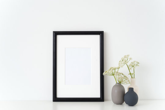 Elegant black portrait a4 frame mock up with a Aegopodium podagraria in little vases. Mockup for quote, promotion, headline, design. Template for small businesses, lifestyle bloggers, social media