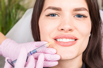 Happy relaxed smiling patient woman in a comet clinic. Procedure for lip correction with fillers....
