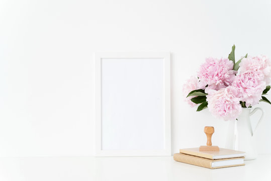 White blank frame mockup. Still life composition, floral bouquet of pink peonies in jug, stamp. White background, mock up for quote, promotion, design, lifestyle bloggers and social media