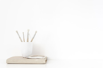 Off to university. Background with stationary, old book, seashells, cup, paint brushes on white wall background, soft home decor. Copy space for text. Empty space for lettering.