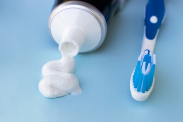 Toothpaste squeezed out from tube and toothbrush on blue background. Dental hygiene concept.