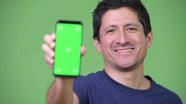 Happy Hispanic man showing phone