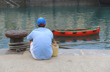 hombre sentado en el puerto mirando al agua  país vasco 4M0A0125-f18