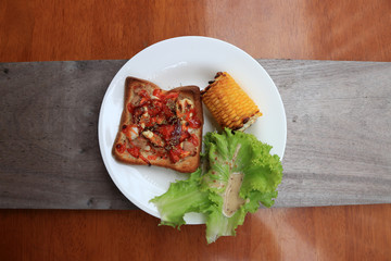 Home made pizza on square sliced bread with grilled Corn and lettuce in the white round plate on the wooden table. Top angle.