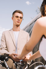 elegant wedding couple holding hands while sitting on scooter