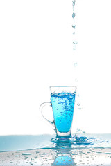 Water splashing into glass of water on white