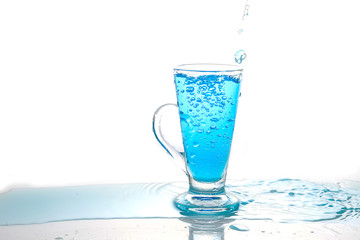 Water splashing into glass of water on white