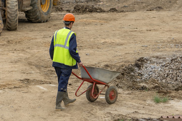 A worker is driving a wheelbarrow at a construction site