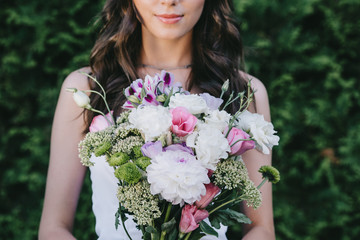 cropped view of beautiful woman posing in wedding dress and holding traditional bouquet