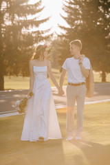 Fototapeta na wymiar happy wedding couple holding hands outdoors with sunlight
