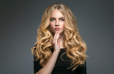 Blonde hairstyle woman beauty with long curly blonde hair over dark background