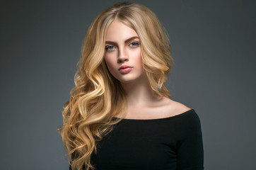 Naklejka premium Blonde hairstyle woman beauty with long curly blonde hair over dark background