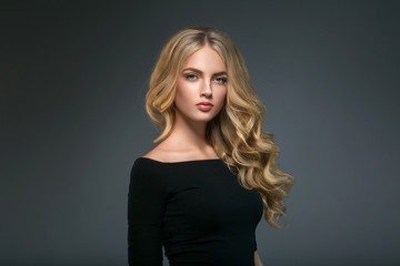 Blonde hairstyle woman beauty with long curly blonde hair over dark background - obrazy, fototapety, plakaty