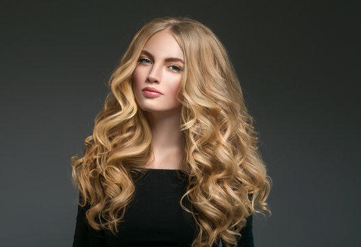 Blonde hairstyle woman beauty with long curly blonde hair over dark background