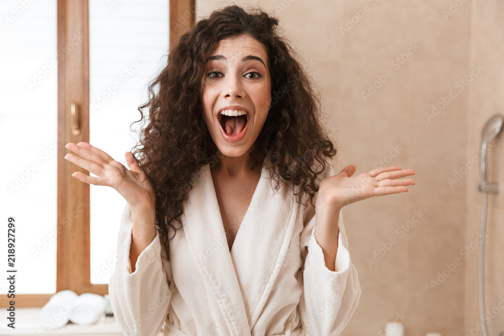 Sticker Beautiful surprised young cute woman looking camera in bathroom.