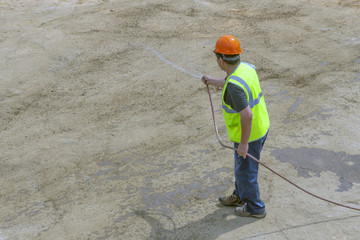Worker at the construction site water from a hose