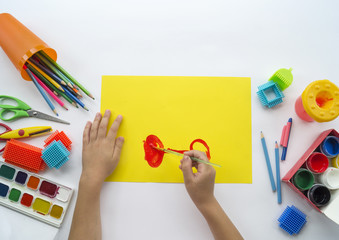 A child draws a picture of a bicycle with paints.