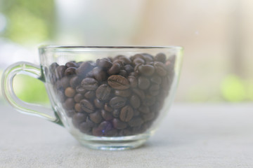 Good morning! Coffee beans in a transparent cup. Light textured background, toned photo. Close-up....