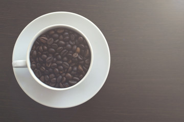 White mug with coffee beans. Wooden table. Toned photo. Copy space