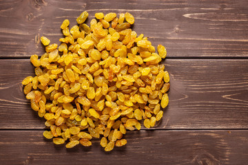 Lot of whole dry golden raisins sultana variety heap flatlay on brown wood