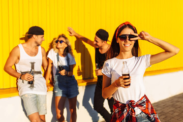 portrait of beautiful guys on the background of a group of friends, group of young people with glass bottles with a drink stand near the supermarket, on a yellow background, friends come off in full