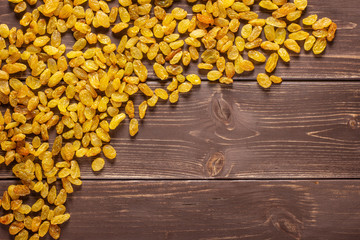 Lot of whole dry golden raisins sultana variety left upper corner flatlay on brown wood