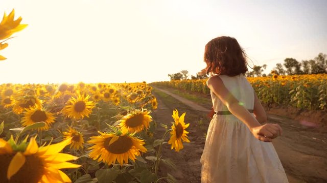 little girl running across the field with sunflowers at sunset. slow motion video. girl runner in the field at sunset sunflowers. girl sunlight lifestyle runs the concept of sunflowers
