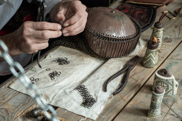 Master weaves chain mail from metal rings. Dragon scales. 