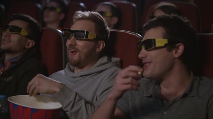 Man friends eating popcorn at 3d cinema movie. Men have fun at cinema. Spectators of cinema eat pop corn in 3d glasses. People enjoy 3d comedy film. Male relaxing at movie hall. Movie entertainment