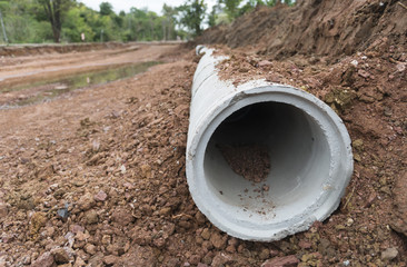Concrete Drainage Pipe row on a Construction Site near ditch. Concrete pipe stacked sewage water system aligned on site. - obrazy, fototapety, plakaty