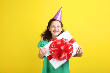 Beautiful young girl with gift box on yellow background