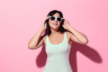 Young woman with sunglasses on pink background