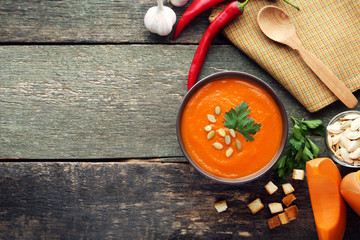 Pumpkin soup with seeds and parsley in bowl on wooden table