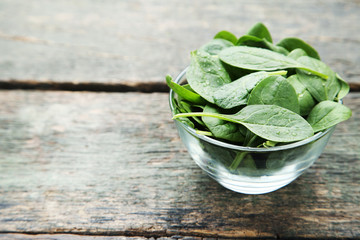 Spinach leafs in bowl on grey wooden table