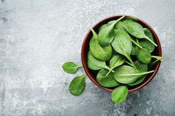 Spinach leafs in bowl on grey wooden table