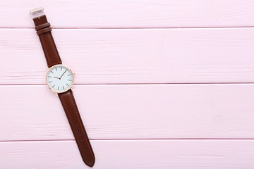 Wrist watch on pink wooden table