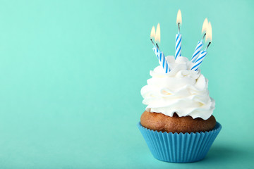 Tasty cupcake with candles on mint background