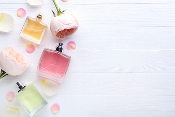 Perfume bottles with peony roses on white wooden table