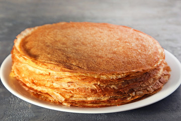 Heap of pancakes in plate on grey wooden table