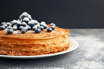 Pancakes with blueberries and powdered sugar on grey wooden table