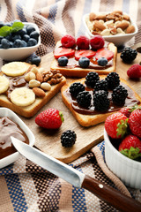 Toasts bread with berries on brown cutting board