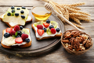 Toasts bread with berries on cutting board with various nuts